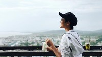 Meski berambut cepak, Miss Vietnam 2017 ini tetap tampil mempesona. Ia terlihat sedang meminum segelas milkshake sambil menikmati pemandangan yang ada. Foto: Instagram hhennie.official