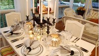Sebuah tempat lilin besar membuat meja makan ini berkesan klasik. Piranti makan yang juga simpel cocok dijadikan ide menata meja makan untuk makan malam di rumah nenek.  Foto: Istimewa