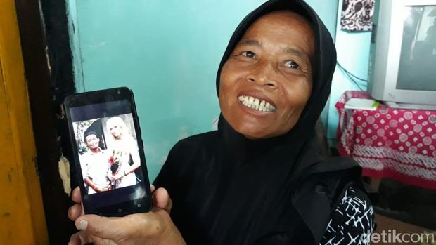 Juwariyah menunjukkan foto pernikahan anaknya dengan Polly. 