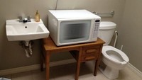 Desain toilet ini cukup aneh dan mengundang tawa. Di antara wastafel dan closet, ada meja terbentang dengan microwave yang terpasang di sana. Mungkin biar lebih praktis menghangatkan makanan ya? Foto: Istimewa
