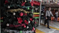 Seorang warga melintas diantara ornamen berupa pohon natal di TPO Kota Tua, Jakarta, Selasa (18/12/2018).