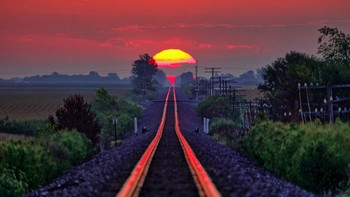 Cahaya matahari terbenam yang memantul di atas rel kereta. (Foto: Brightside)
