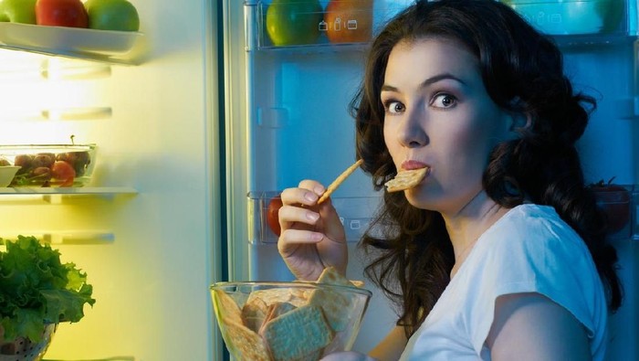 186218666 a hungry girl opens the fridge