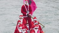 Tak cuma menggunakan papan selancar, Santa bersama kawan-kawan lainnya memilih menggunakan perahu untuk berkeliling kota Venice, Italia. Marco Secchi/Getty Images.