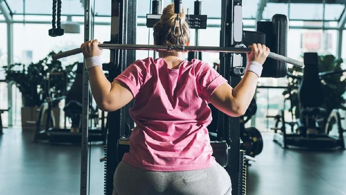 gemuk kegemukan obesitas fitness overweight woman working out on training apparatus