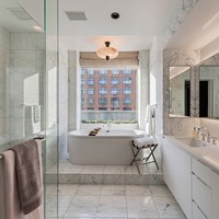 Kamar mandi mewah serba putih berlantai marmer. Pada bagian bath tub juga terdapat jendela kaca besar yang berhadapan langsung dengan gedung berwarna merah bata. Foto: Dok. People/Stribling & Associates