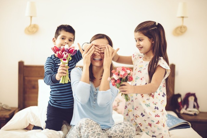 ilustrasi hari ibu Sweet little girl of 2 years old old brings breakfast to bed to her pregnant mother during the mothers day. SHe is very proud to do that. SHe wear pink pyjama. Photo can be use for Valentines day, fathers day, birthday. A golden doodle dog is laying in a bed.