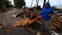 Seorang warga tengah mengumpulkan puing-puing sisa bangunan.