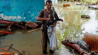 Seorang warga mengumpulkan barang-barang berharga yang masih dapat diselamatkan dari rumahnya yang hancur akibat tsunami.