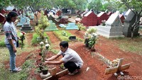 Seorang warga meletakan bunga di makan sanak saudaranya.