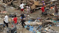 Berjalan melintasi puing-puing bangunan, warga berlarian menuju bangunan yang lebih tinggi.