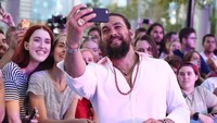Para penggemar ikut masuk dalam frame foto bersama Jason Momoa. Foto: Chris Hyde/Getty Images