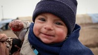 Seorang balita asal Suriah yang sedang mengungsi di Irak terlihat tersenyum ceria di tengah konflik dan cuaca di musim dingin yang menusuk. UNICEF terus mendukung 10.000 anak-anak di pengungsian untuk mendapatkan pakaian hangat. Istimewa/UNICEF/Sparks.