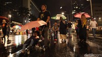 Para warga menggunakan payung untuk terhindar dari hujan.