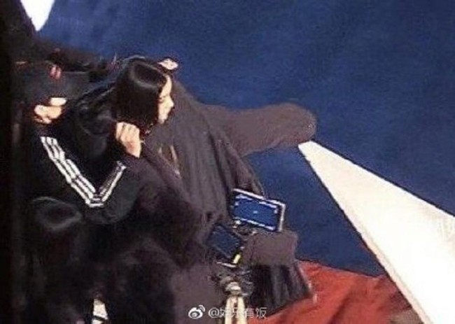 Menurut laporan AsiaOne, foto-foto yang dibagikan di Weibo itu memperlihatkan seorang wanita mengenakan jas hitam berlutut di lantai dan melepaskan sepatu bot serta kaus kaki wanita yang diduga Angelababy, dan kemudian menggantinya dengan sepatu berhak tinggi. Foto: Instagram/@angelababyct