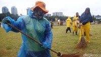 Petugas membersihkan rumput di kawasan Monas dari sampah.