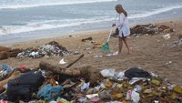 Seorang turis turut membersihkan sampah yang berserakan di kawasan Pantai Kuta, Badung, Bali, Selasa (1/1/2019). ANTARA FOTO/Nyoman Hendra Wibowo.