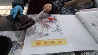 Peletakan kertas harus sesuai dengan gambar yang hendak diwarnai. Biasanya satu kertas tahun baru berisi sampai 6 warna. Maka pengrajin harus melakukan 6 kali pewarnaan dengan teknik yang sama (Bonauli/detikTravel)