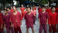 Para peserta program detoksifikasi di kuil Wat Thamkrabok berbaris menyanyikan lagu nasional Thailand. Peserta diharapkan mengikuti program minimal sampai seminggu. (Foto: Paula Bronstein/Getty Images)