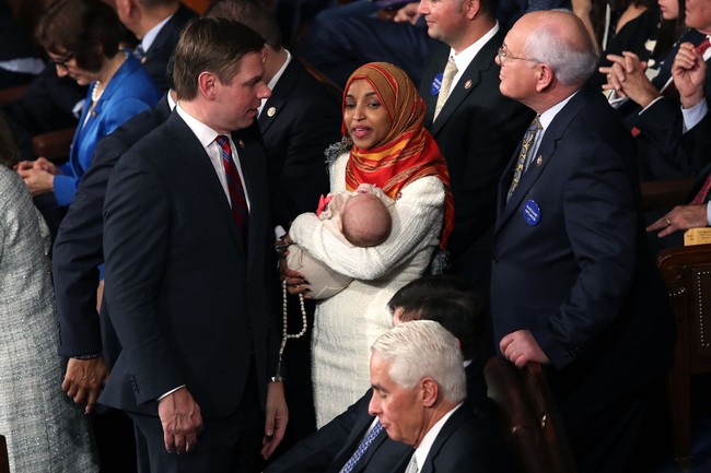 Meski jadi satu-satunya wanita berhijab. Ilhan Omar tampak cair berkomunikasi dengan para anggota. Terlihat ia menggendong bayi putri dari Eric Swalwell. Foto: Getty Images/Win McNamee