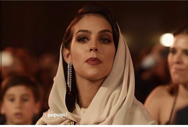 Georgina Rodriguez yang sudah memiliki satu putra dari Ronaldo ini memakai scarf panjang di kepala untuk menghormati penyelenggara acara. Ia memadukan scarf tersebut dengan gaun bernuansa emas. Foto: Instagram