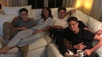 Santai bersama keluarga, Romeo yang memegang gelas minuman memamerkan senyum manisnya. Ada Brooklyn dan Cruz duduk di sebelah ibu mereka. Foto: Instagram romeobeckham