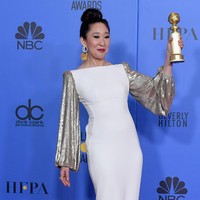 Gaun putih boat neck dengan panel sequin emas di bagian lengan ini dirancang oleh Stella McCartney. Dalam garis yang minimalis, gaun ini membuat aura bintang Sandra Oh begitu memancar. Foto: Getty Images