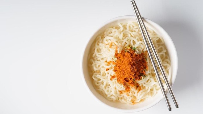 Instant noodle and spicy seasoning in white bowl with chopstick