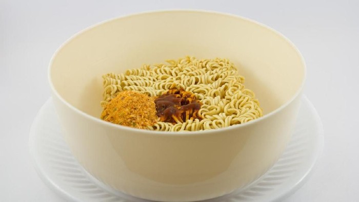 Instant noodle and spicy seasoning in white bowl with chopstick