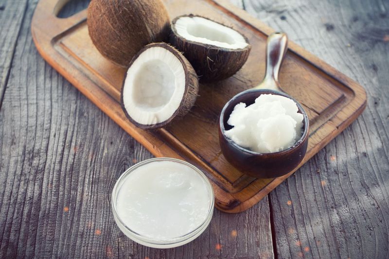 Coconut with coconut oil in jar on wooden background