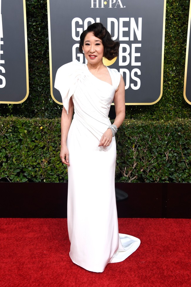 Sandra Oh hadir di karpet merah Golden Globes 2019, Senin (7/1/2019) berbalut gaun putih Versace yang memikat. Aksen draperi pada satu bagian gaun menambah kesan modern yang chic untuk karakter aktris serial Greys Anatomy ini. Foto: Getty Images