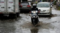 Para pengendara motor tetap nekat melintasi genangan.