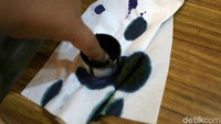 Seorang siswa mencelupkan jarinya ke tinta.
