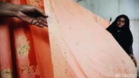 Seorang perajin sedang menjemur kain batik.