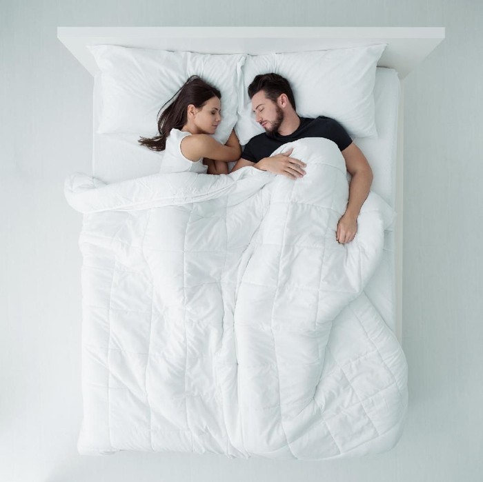 Loving couple relaxing and sleeping in bed, top view