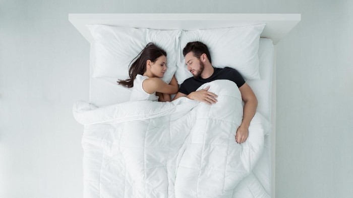 Loving couple relaxing and sleeping in bed, top view