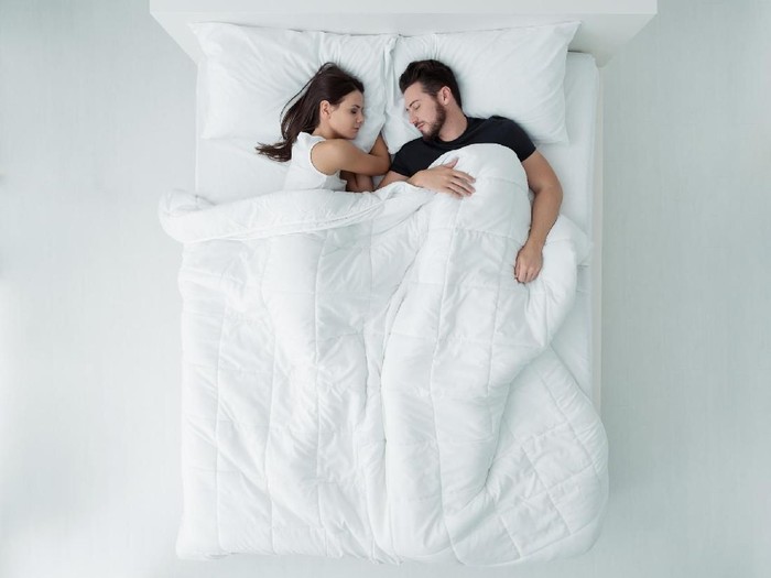 Loving couple relaxing and sleeping in bed, top view