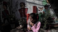Seorang warga melintas di kawasan gang sempit permukiman jembatan lima yang temboknya sudah dipenuhi mural yang ciamik.