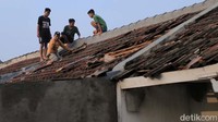 Warga memberbaiki atap rumahnya yang rusak.