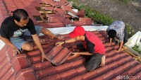Bahu membahu mereka merapikan kembali genting yang sebelumnya berantakan diterjang angin.