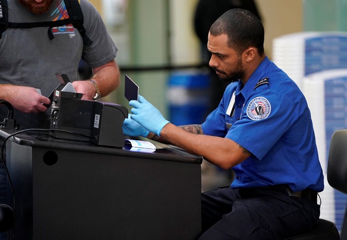 An employee with the Transportation Security Administration (TSA) checks the documents of a traveler at Reagan National Airport in Washington, U.S., January 6, 2019.      REUTERS/Joshua Roberts
