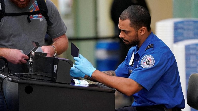 An employee with the Transportation Security Administration (TSA) checks the documents of a traveler at Reagan National Airport in Washington, U.S., January 6, 2019.      REUTERS/Joshua Roberts