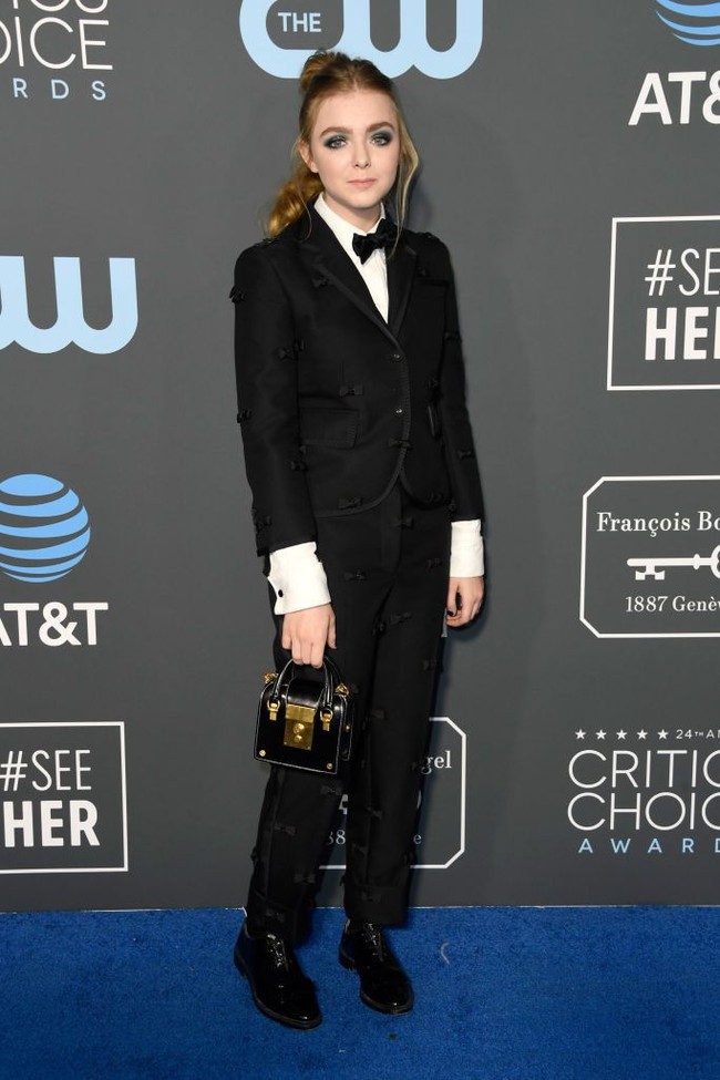 Setelan yang dihiasi bordiran pita karya Thom Browne menjadi pilihan aktris cilik Elsie Fisher. Ia lalu menyempurnakan gayanya dengan handbag mungil nan eksentrik. (Foto: Getty Images)