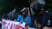 Massa aksi datang sekitar pukul 17.30 WIB. Wajah mereka ditutup plastik hitam.