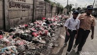 Dua orang pelajar melintas di depan tumpukan sampah di Jalan Marunda Makmur, Jakarta.