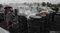 Seorang warga sedang membakar batok kelapa untuk dibuat arang.