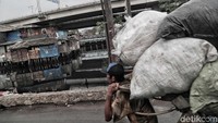 Seorang pemulung melinas diantara pemukiman kumuh.