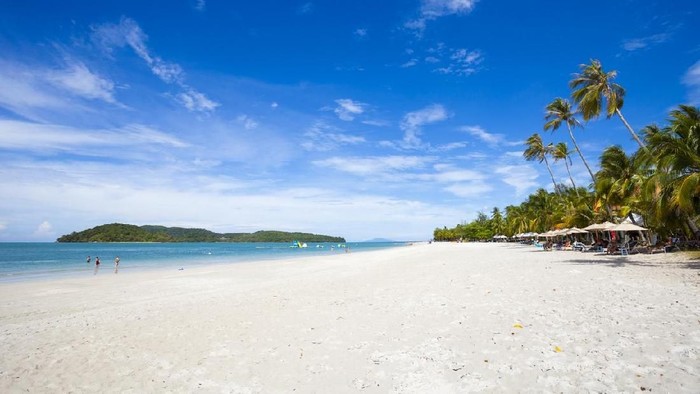 Langkawi, Malaysia - March 9, 2011: One of the beaches in Langkawi, Malaysia. People can be seen sunbathing and playing in the water. Other islands can be seen in the background.