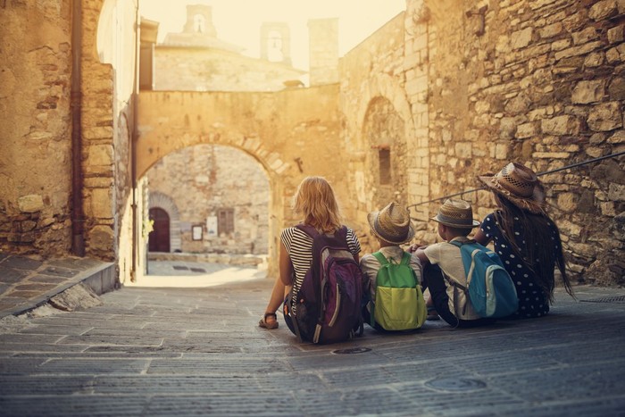 Mother and kids tourists sightseeing beautiful Italian town of Campiglia Marittima. Sunny summer day. Italy, Tuscany.