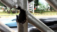 Salah satu besi di bagian tangga JPO nampak berkarat dan bolong.